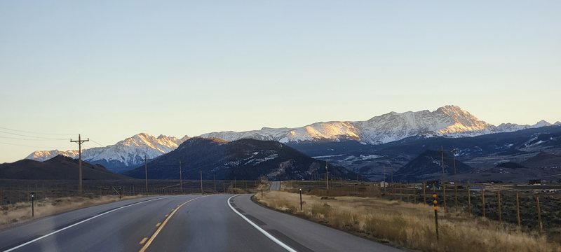 An open road toward snow-capped mountains in Colorado.
