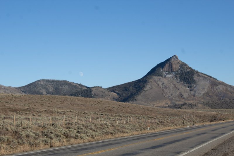 Sharp conical peak beside a road under blue sky