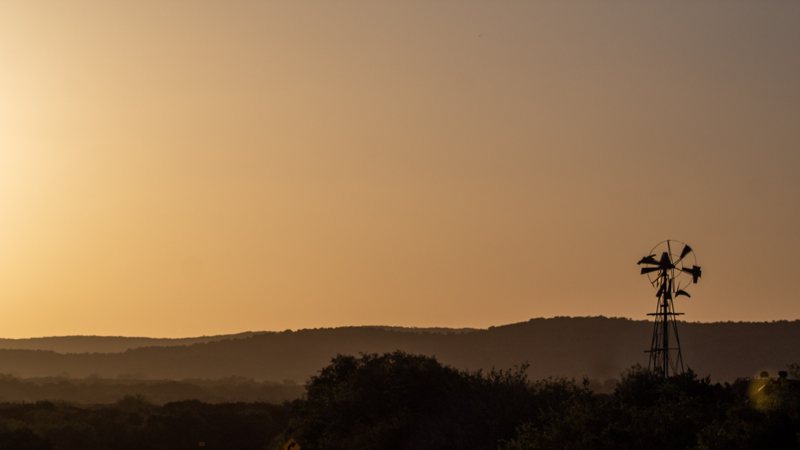 A windmill silhouetted against a Texas sunset.