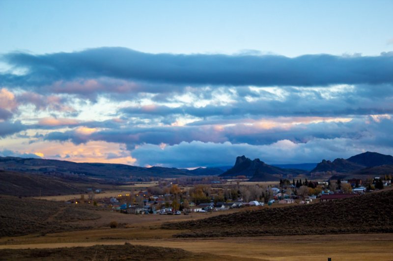 Mountain town at dusk beneath a rock butte and pink clouds
