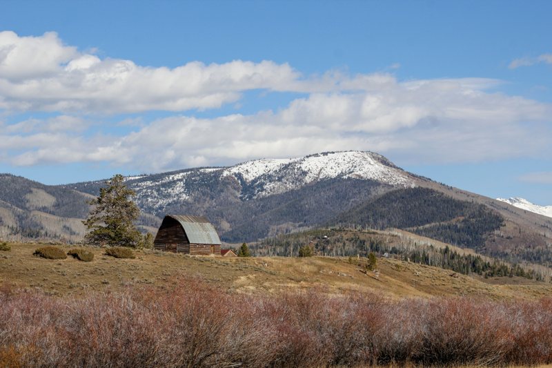 Old wooden barn under a snow-capped mountain